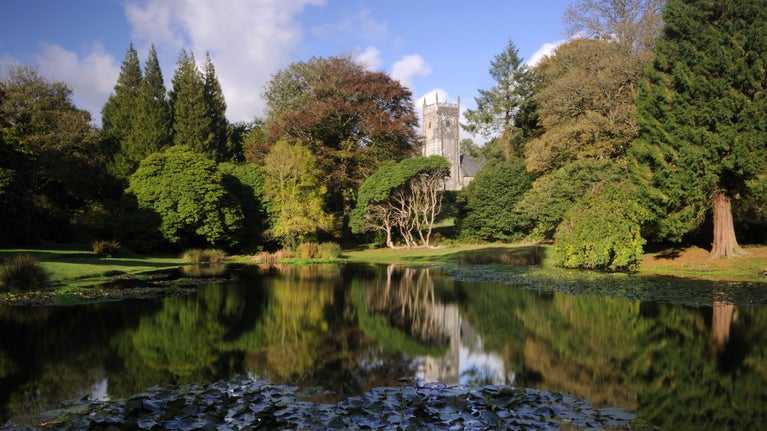 The church of St James's (Not NT), Wilderness Pond and reflections in the garden at Arlington Court, Devon in October